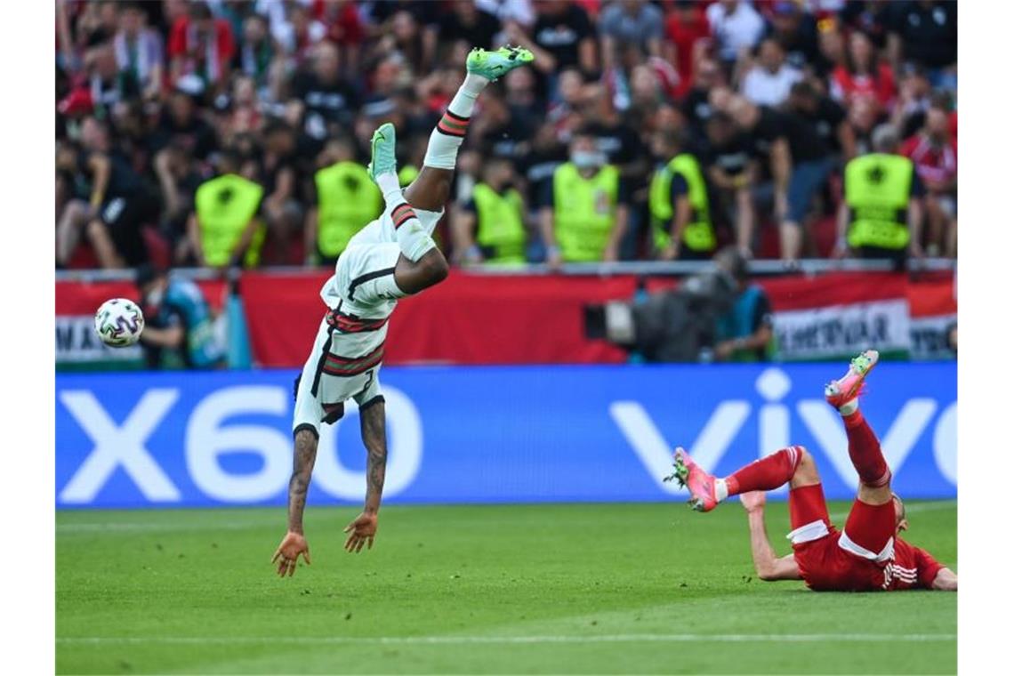 Portugal besiegt Ungarn mit einem „teuflischen Schlussakt“ Nach einem Zweikampf mit dem Ungarn Tamas Cseri fliegt der Portugiese Nelson Semedo (l) durch die Luft. Foto: Robert Michael/dpa-Zentralbild/dpa