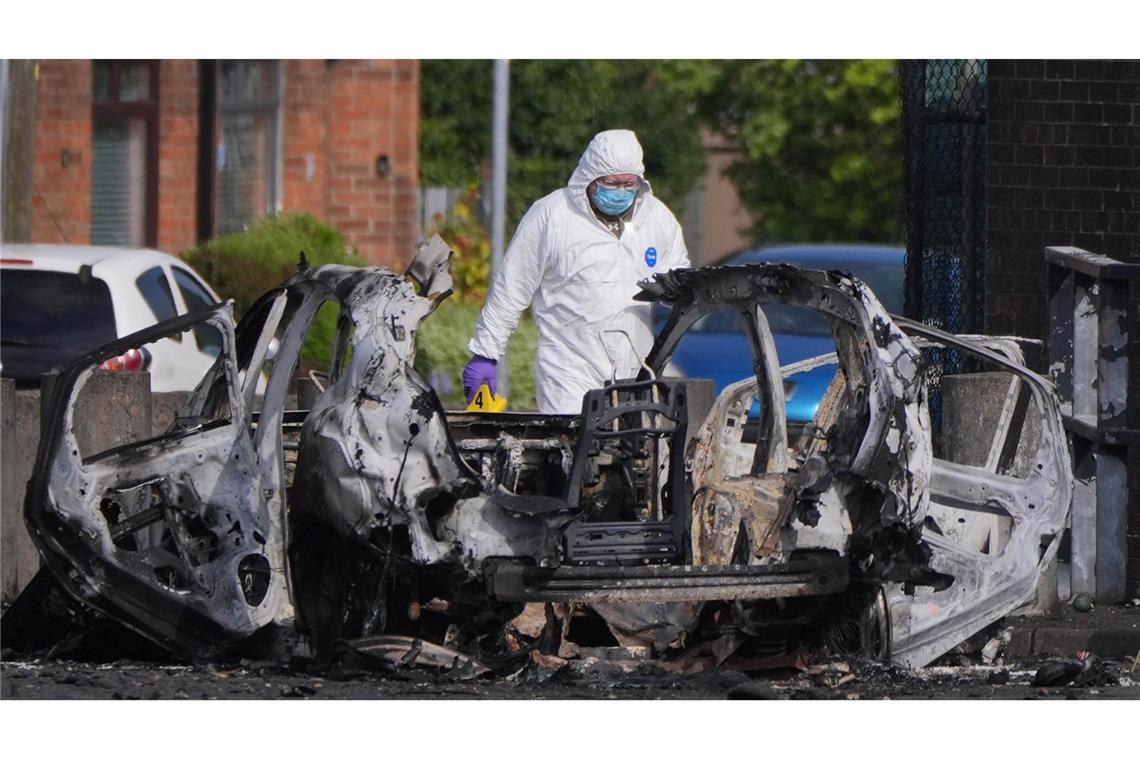 Nach einer Explosion vor einer Polizeistation steht ein Ermittler neben einem zerstörten Auto in Dunmurry, nahe Belfast in Nordirland.