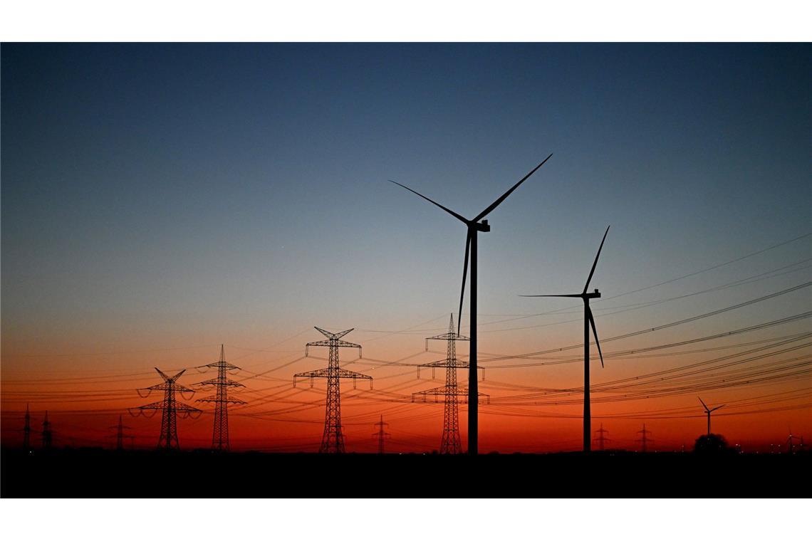 Nach Sonnenuntergang stehen Windräder auf einem Feld bei Pulheim.