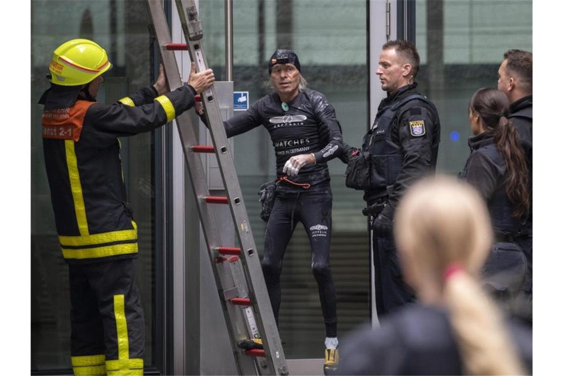 Nachdem er die Fassade des Skyper-Hochhauses wieder hinuntergeklettert war, wird der Extremkletterer von Polizisten in Empfang genommen. Foto: Boris Roessler