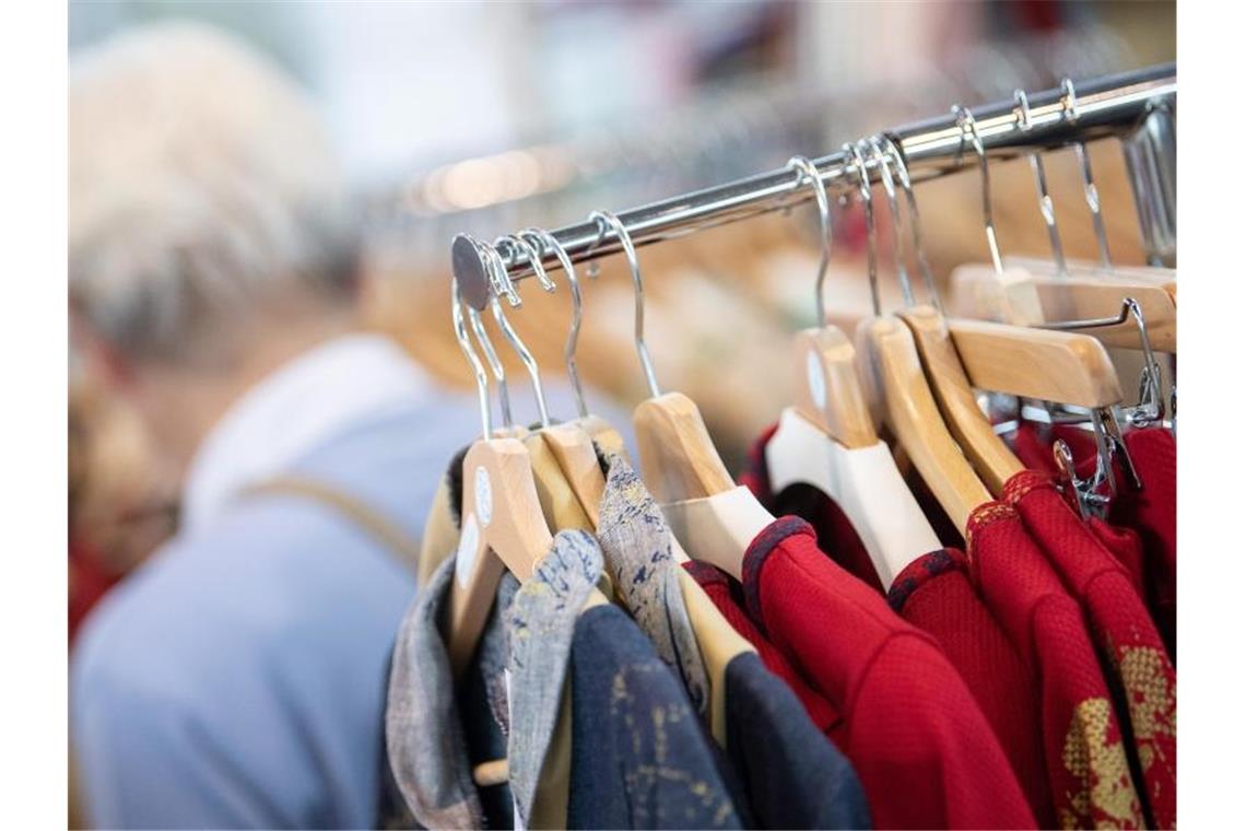 Nachhaltig produzierte Kleidung hängt an Kleiderbügeln auf der Messe „Fair Handeln“ an einem Stand. Knapp jeder dritte Verbraucher in Deutschland ist bereit, für nachhaltige Produkte oder Dienstleistungen einen Preisaufschlag zu zahlen. Foto: Sebastian Gollnow/dpa