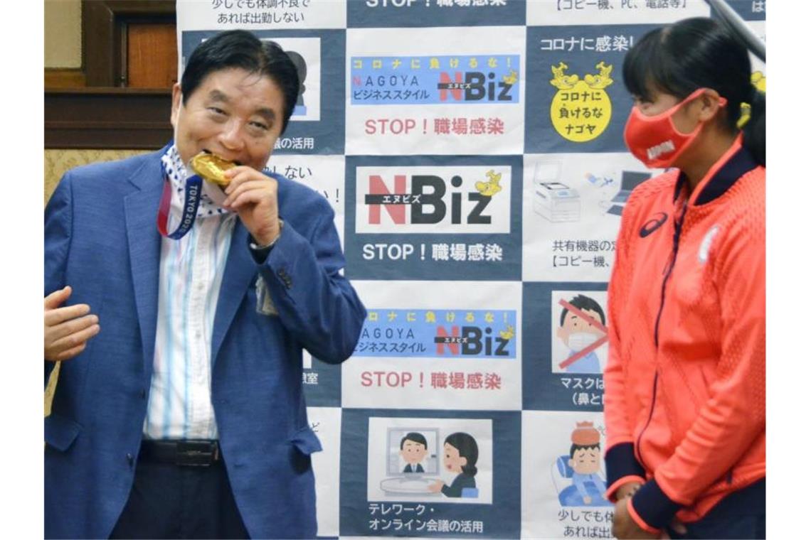 Japanerin bekommt nach Bürgermeister-Biss neue Gold-Medaille Nagoyas Bürgermeister Takashi Kawamura (l) biss in die Gold-Medaille von Miu Goto. Foto: Uncredited/Kyodo News/dpa