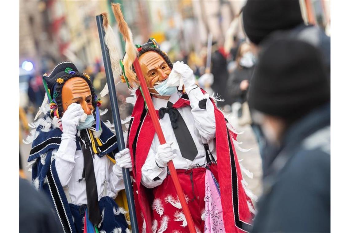 Narren in Rottweil trotzen der Coronaverordnung Narren mit OP-Masken über ihren Gesichtsmasken gestikulieren am Fastnachtsmontag vor Polizisten. Foto: Sebastian Gollnow/dpa
