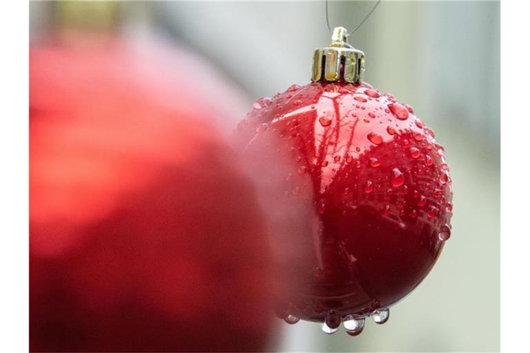 Nasse Christbaumkugeln hängen nach einem Regen an einem Baum. Foto: Sebastian Gollnow/dpa