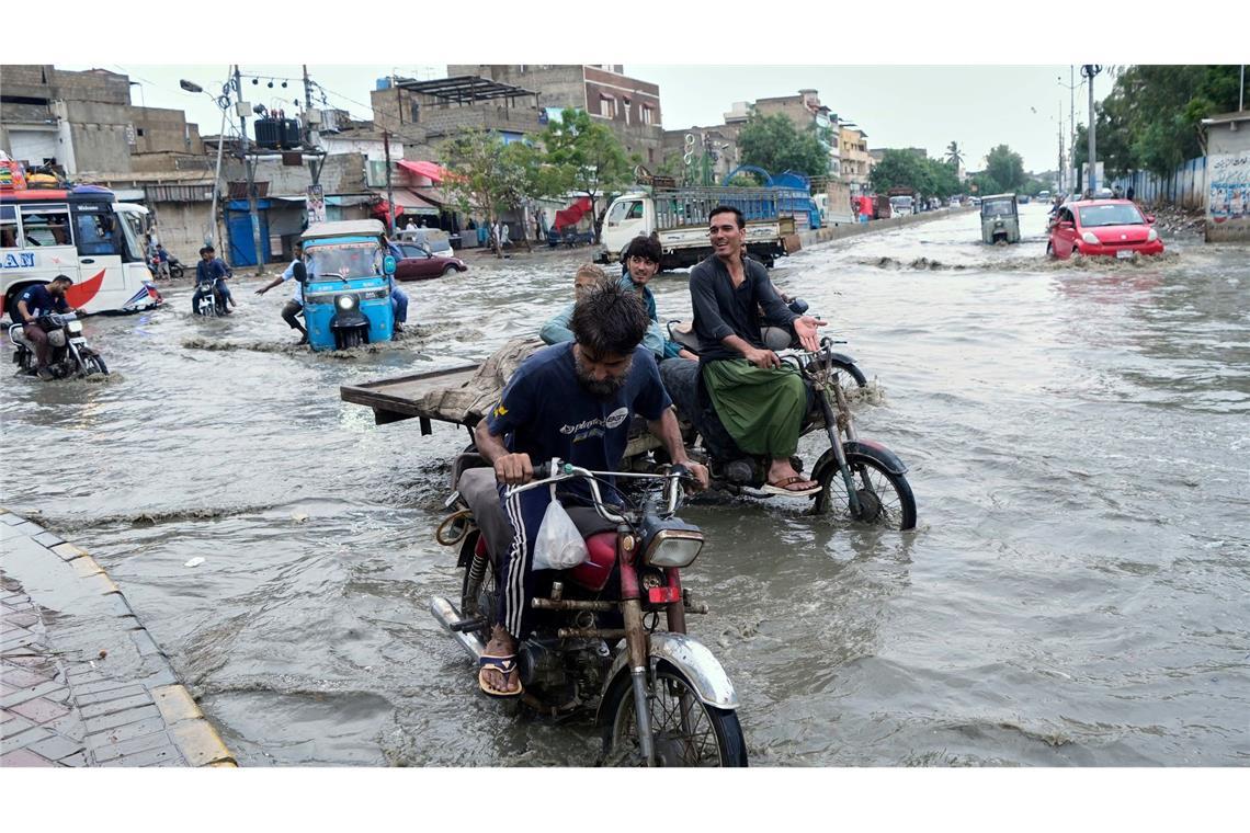 Nasse Füße bekommen diese Motorradfahrer nach schweren Regenfällen im pakistanischen Karachi.
