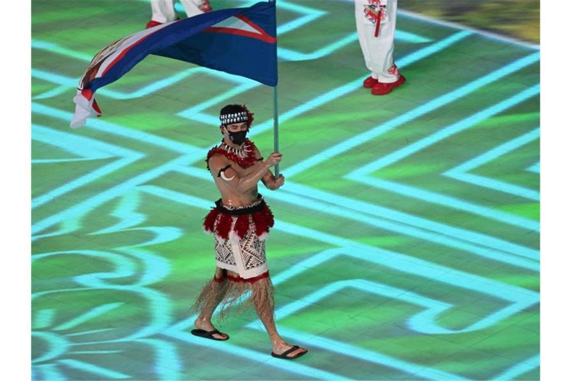 Olympia bei schwierigen Gastgebern: Winterspiele eröffnet Nathan Crumpton trägt die Flagge für Amerikanisch-Samoa ins Stadion. Foto: Robert Michael/dpa-Zentralbild/dpa