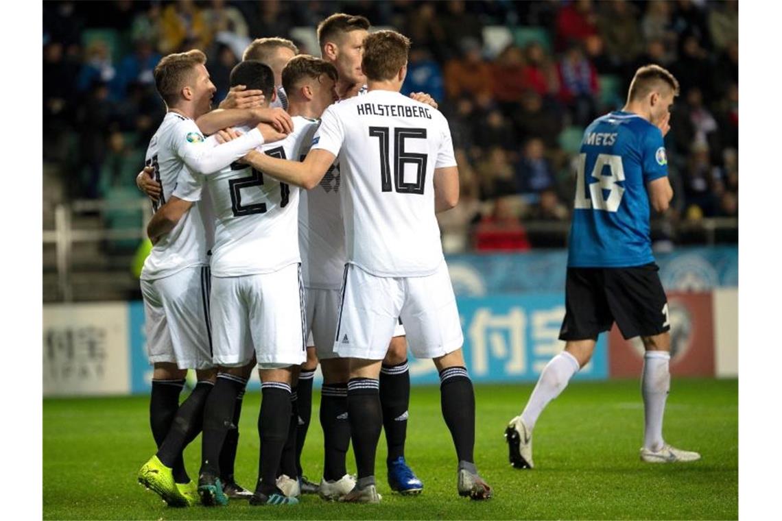 Neben den über das 2:0 jubelnden deutschen Spielern (l) geht der Este Karol Mets nach seinem Eigentor frustriert davon. Foto: Federico Gambarini/dpa