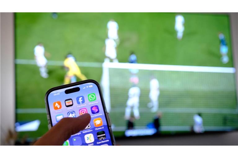 Nebenbei mal daddeln: Während das Fußballspiel läuft, schauen viele Zuschauer nebenbei aufs Handy. (Symbolbild)