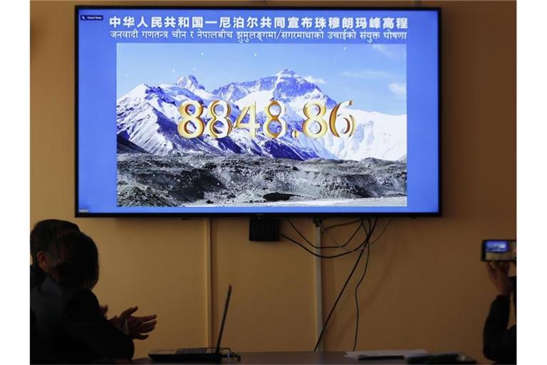 Nepalesische Regierungsbeamte schauen eine gemeinsame Fernsehübertragung von Nepal und China, in der die offizielle Höhe des Mount Everests bekanntgegeben wird. Foto: Niranjan Shrestha/AP/dpa