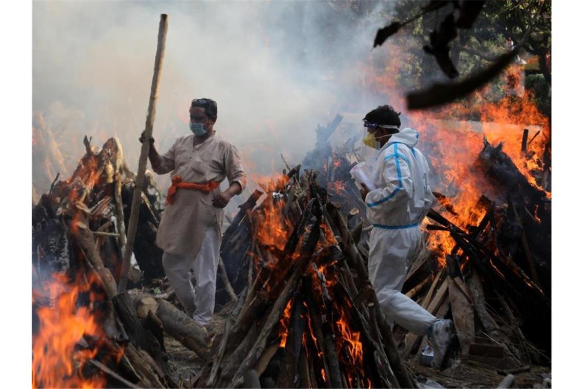 Neu-Delhi: Angehörige neben brennenden Scheiterhaufen von Opfern, die an den Folgen einer Corona-Infektion gestorben sind. Foto: Naveen Sharma/SOPA/ZUMA/dpa