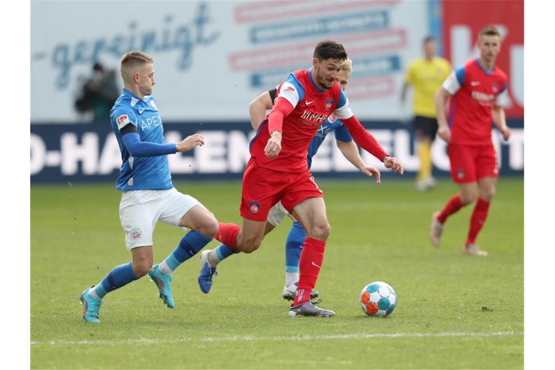 Nico Neidhart (l) und Simon Rein (r) von Hansa Rostock gegen Tim Kleindienst vom 1. FC Heidenheim. Foto: Danny Gohlke/dpa