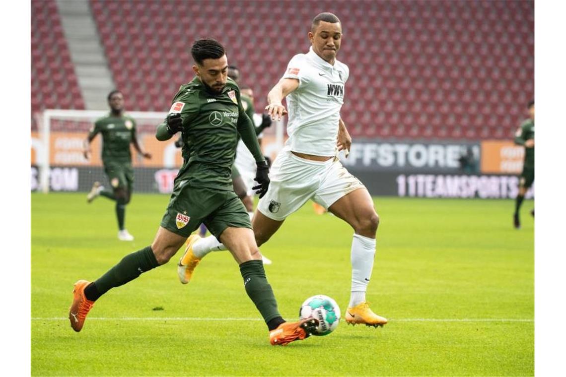 Nicolas Gonzalez von Stuttgart und Felix Uduokhai von Augsburg (l-r.) im Zweikampf um den Ball. Foto: Matthias Balk/dpa