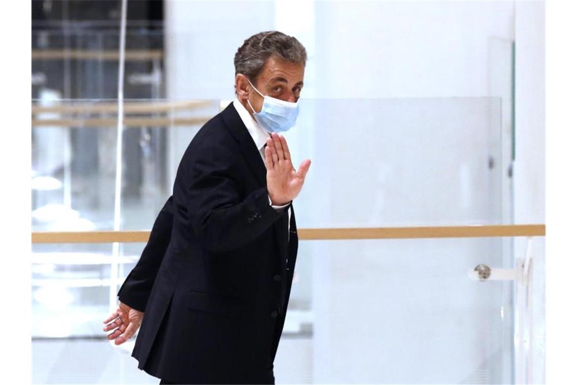 Nicolas Sarkozy, ehemaliger Präsident von Frankreich, winkt beim Verlassen des Gerichtssaals. Frankreichs ehemliger Präsident Sarkozy steht wegen vermuteter Bestechung und unerlaubter Einflussnahme in Paris vor Gericht. Foto: Michel Euler/AP/dpa