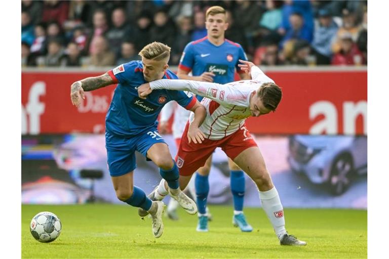 Niklas Dorsch von Heidenheim (l.) und Regensburgs Max Besuschkow kämpfen um den Ball. Foto: Armin Weigel/dpa