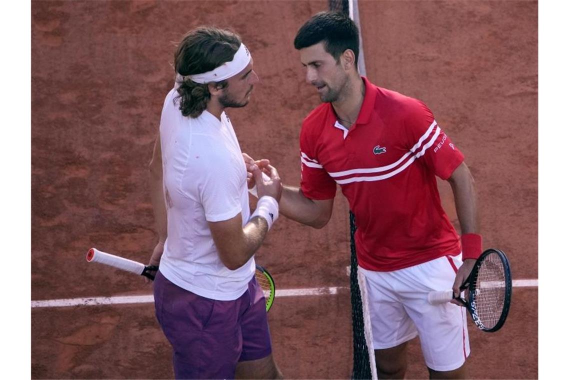 Novak Djokovic (r) und Stefanos Tsitsipas geben sich nach der Partie die Hand. Foto: Christophe Ena/AP/dpa