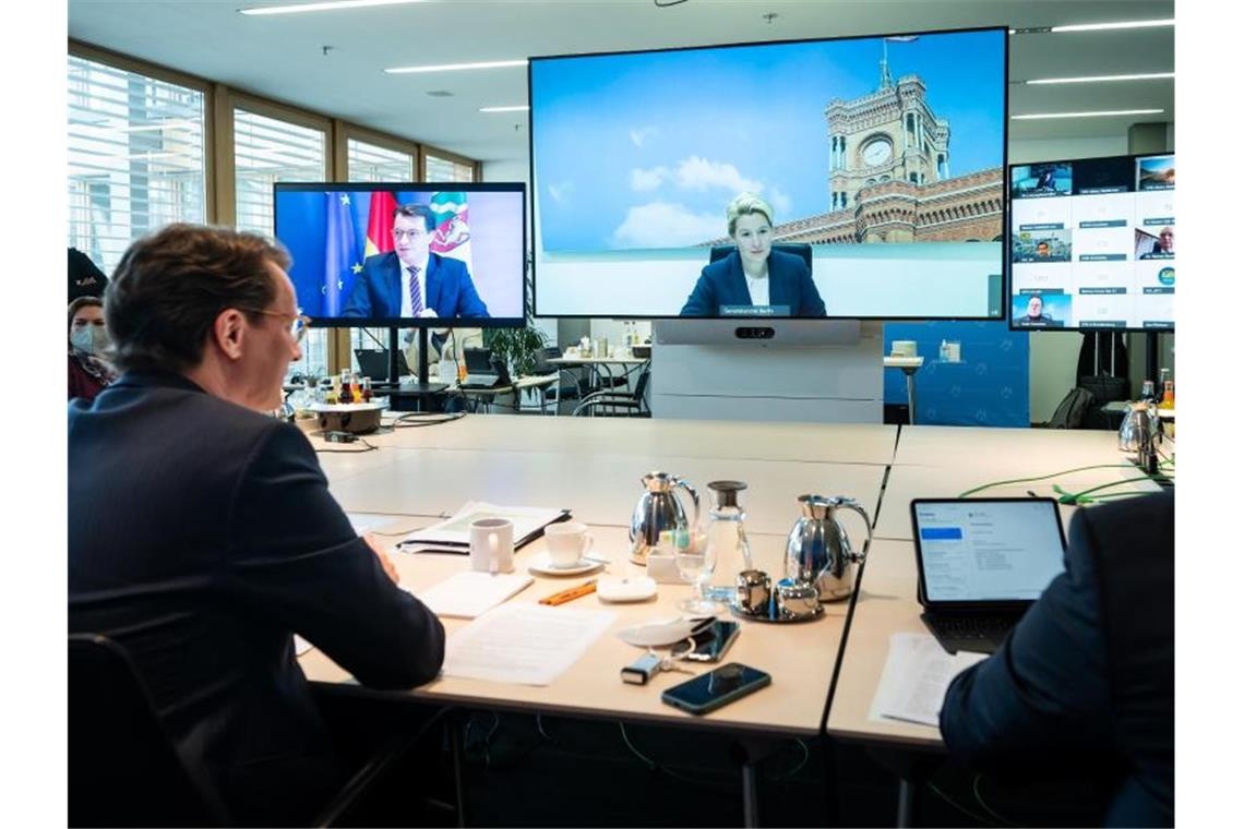 NRW-Ministerpräsident Hendrik Wüst (l.), während der Videokonferenz. Auf dem großen Bildschirm ist Berlins Regierende Bürgermeisterin Franziska zugeschaltet. Foto: Bernd von Jutrczenka/dpa