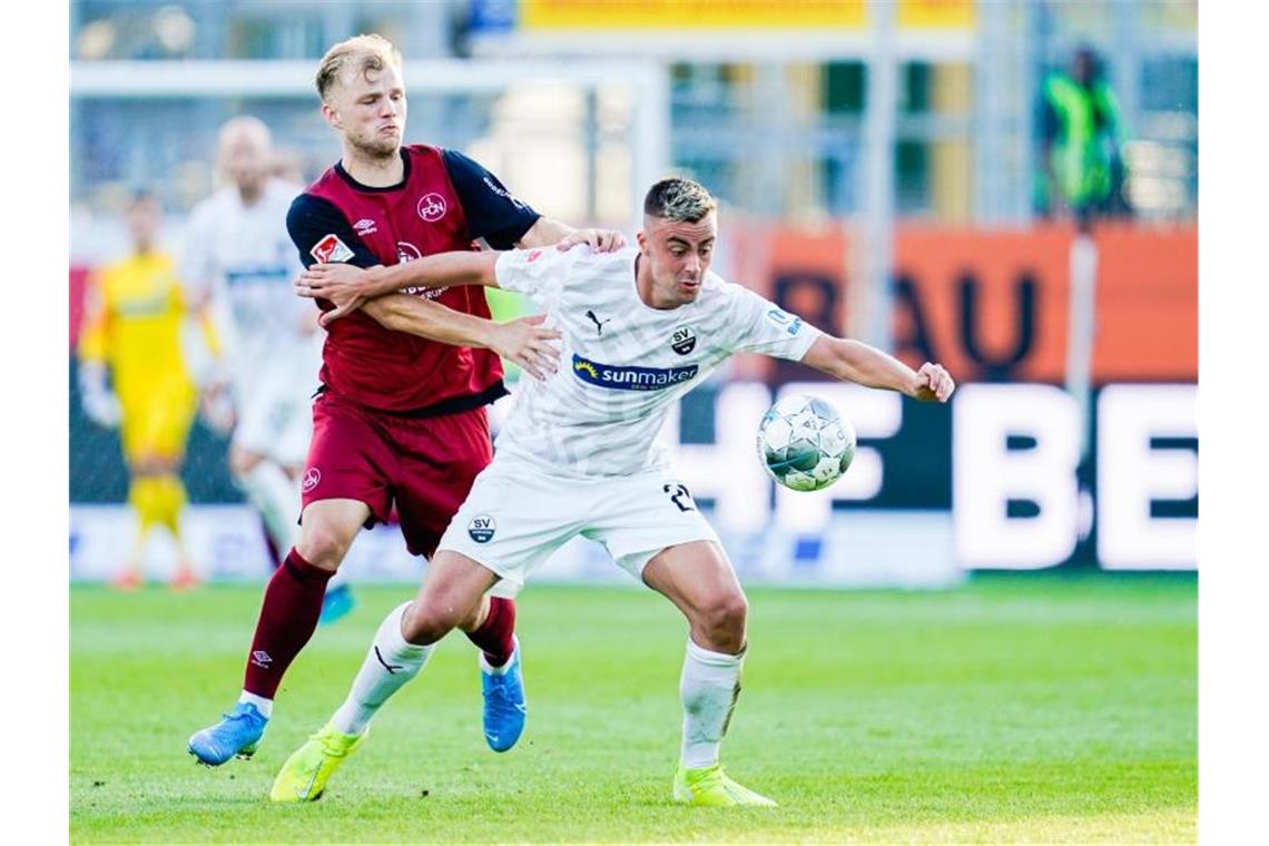 Nürnbergs Johannes Geis (l.) und Sandhausens Philipp Förster kämpfen um den Ball. Foto: Uwe Anspach/Archivbild