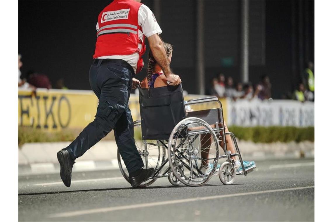 Nur 40 der 68 gestarteten Teilnehmerinnen kamen beim Marathon in Doha ins Ziel: Ein Sanitäter bringt eine erschöpfte Läuferin von der Strecke. Foto: Michael Kappeler