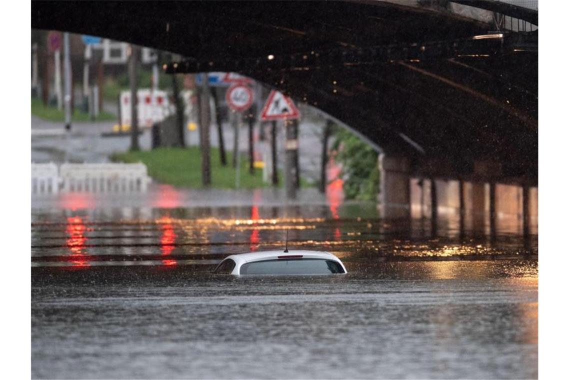 Nur das Dach eines Autos schaut noch aus dem Wasser, das eine Bahnunterführung in Köln geflutet hat. Foto: Marius Becker/dpa