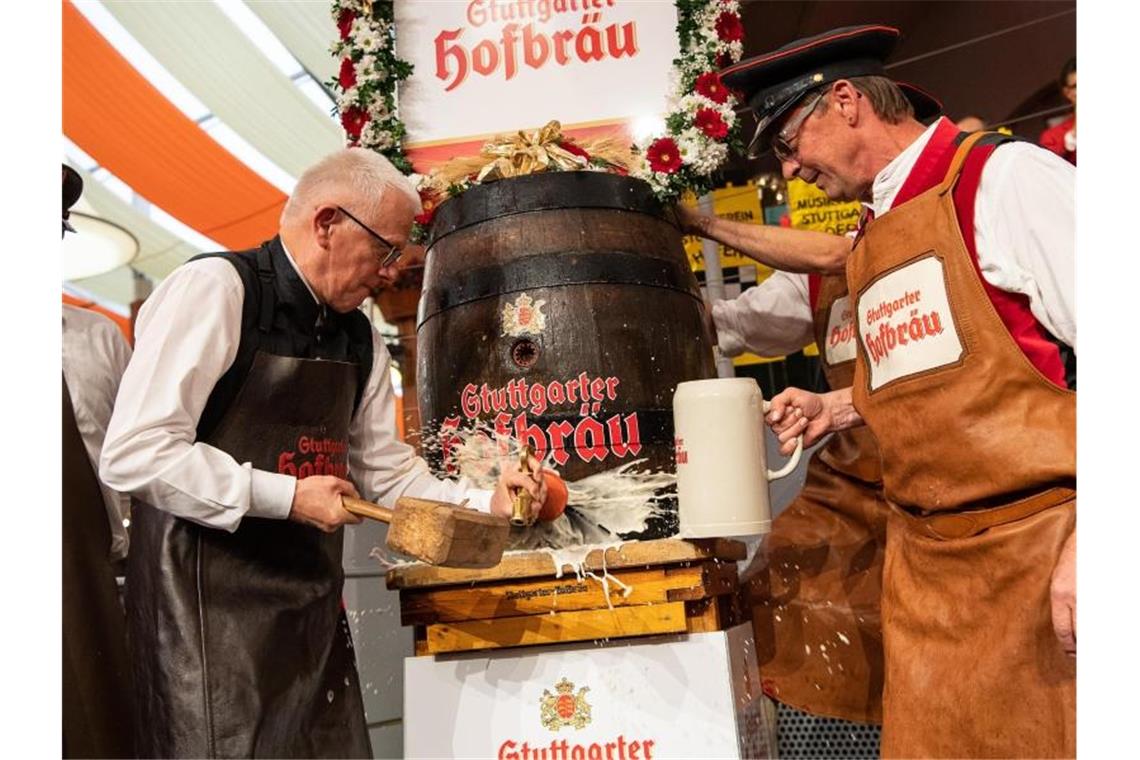 Oberbürgermeister Fritz Kuhn (l) sticht zu Beginn des 174. Cannstatter Volksfests das erste Fass Bier an. Foto: Sebastian Gollnow