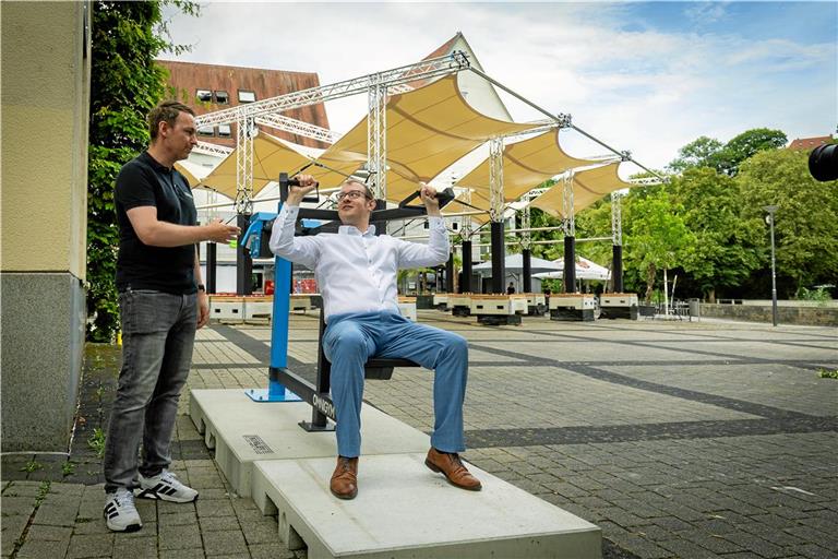 Oberbürgermeister Maximilian Friedrich lässt sich von Felix Mattl die Schulterpresse erklären. Sie ist eines von sieben neuen Fitnessgeräten am Willy-Brandt-Platz. Foto: Alexander Becher
