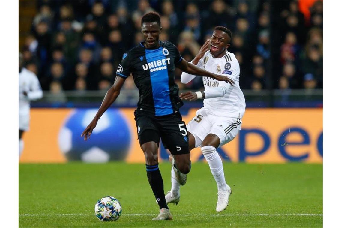 Odilon Kossounou (l) vom FC Brügge und Vinicius Junior (r) von Real Madrid kämpfen um den Ball. Foto: Bruno Fahy/BELGA/dpa