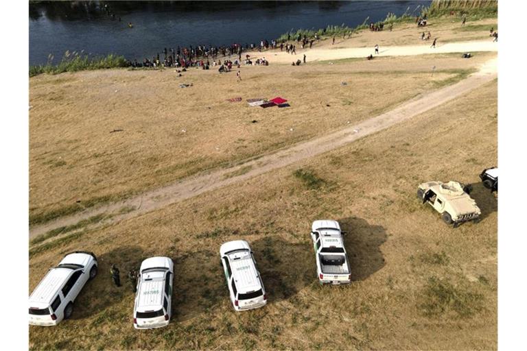 Offizielle Fahrzeuge der US-Grenzkontrolle stehen am Ufer des Flusses Rio Grande in der Nähe eines Lagers von Migranten, viele aus Haiti, nahe der Del Rio International Bridge. Foto: Julio Cortez/AP/dpa