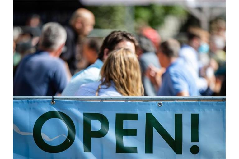 „Open“ steht auf einem Banner an einem Biergarten geschrieben. Foto: Christoph Schmidt/dpa
