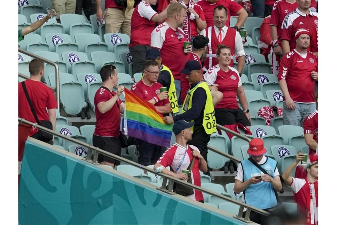 Ordner nehmen zwei Dänemark Fans eine Regenbogen-Fahne ab. Foto: Darko Vojinovic/Pool AP/dpa