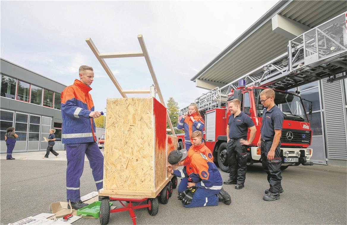 Original und Fälschung: Die „Großen“ der Backnanger Jugendfeuerwehr basteln für den Festumzug am Sonntag einen Leiterwagen. Mit dabei Achim Döring (links mit der Farbwalze) und Nico Zander (schwarze Kappe) sowie Katrin Schäfer (dahinter) und Amelie Gall (ganz hinten). Der Nachbau kommt dem echten Einsatzwagen schon recht nahe. Foto: A. Becher