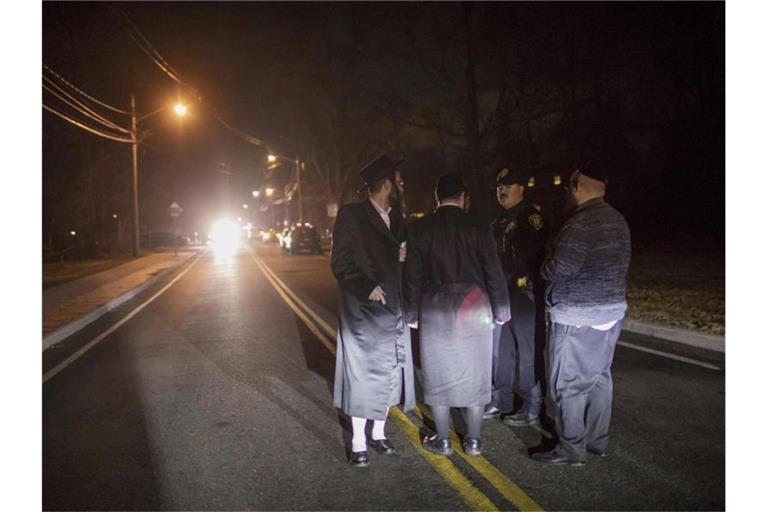 Orthodoxe Juden sprechen nach dem Messerangriff in der Ortschaft Monsey mit einem Polizeibeamten. Foto: Allyse Pulliam/AP/dpa