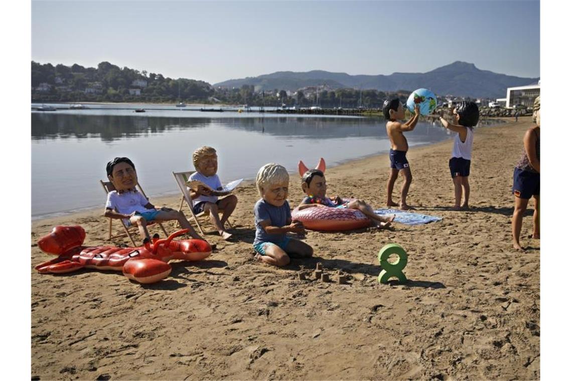 Oxfam-Aktivisten tragen Masken mit den Gesichtern der Teilnehmer des G7-Gipfels am Strand von Hendaye. Foto: Emilio Morenatti/AP