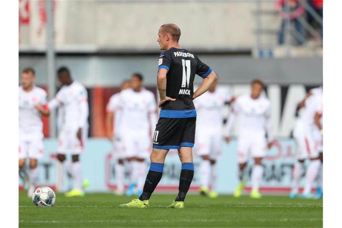 Erste Bayern-Heimpleite seit einem Jahr - S04 nur mit Remis Paderborns Sven Michel zeigt sich enttäuscht nach dem Gegentreffer zum 0:1, während im Hintergrund das Mainzer Team jubelt. Foto: Friso Gentsch/dpa