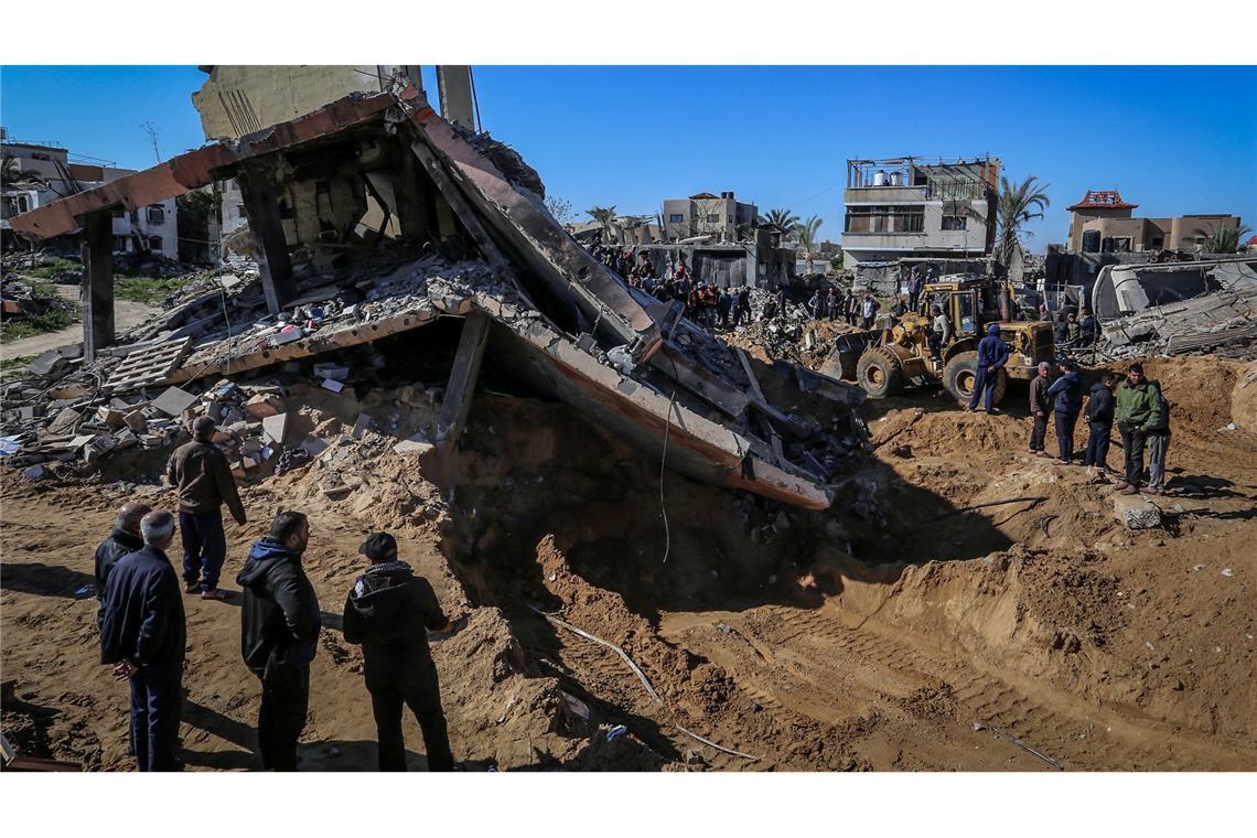 Palästinenser beobachten, wie Mitarbeiter des Zivilschutzes Leichen aus den Trümmern eines durch einen israelischen Luftangriff zerstörten Hauses bergen.