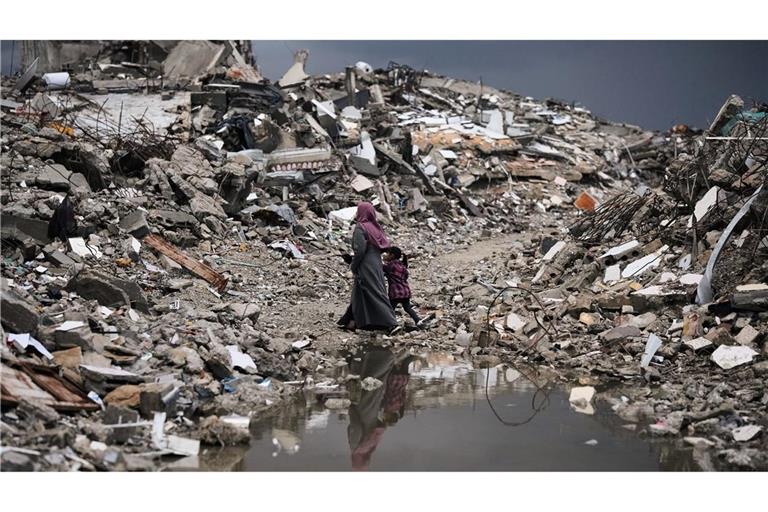 Palästinenser gehen bei stürmischem Wetter durch die Trümmer in Gaza.