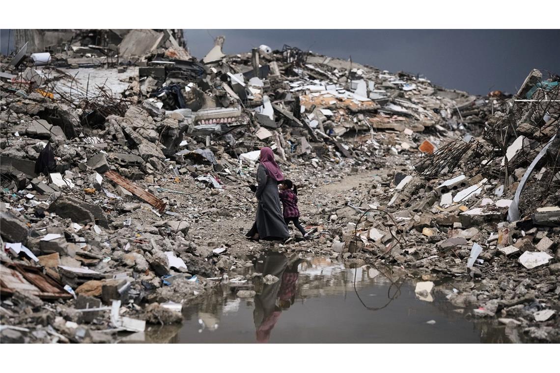 Palästinenser gehen bei stürmischem Wetter durch die Trümmer in Gaza.