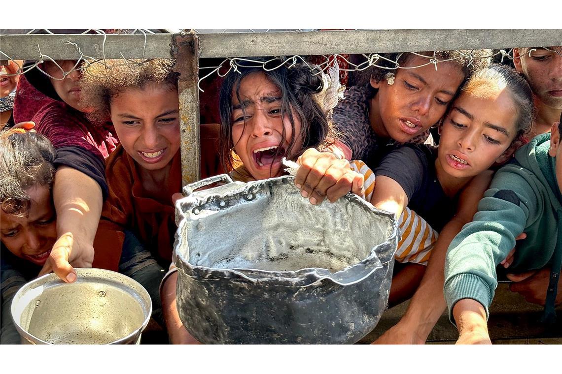 Palästinensische Kinder versuchen im Gebiet Al-Mawasi im Gazastreifen, mit ihren Töpfen Nahrungsmittel zu bekommen, die von einer Wohltätigkeitsorganisation verteilt werden.