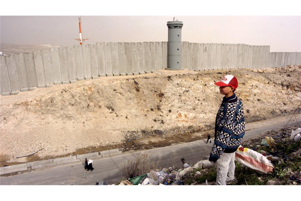 Palästinensischer Junge schaut auf eine Grenzmauer. Israels Regierung will Land im Westjordanland als „Staatseigentum“ registrieren (Archivfoto).