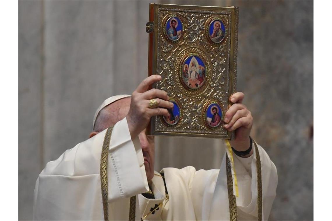 Papst Franziskus hält das Heilige Evangelium während der Ostermesse in die Höhe. Foto: Andreas Solaro/AFP/AP/dpa