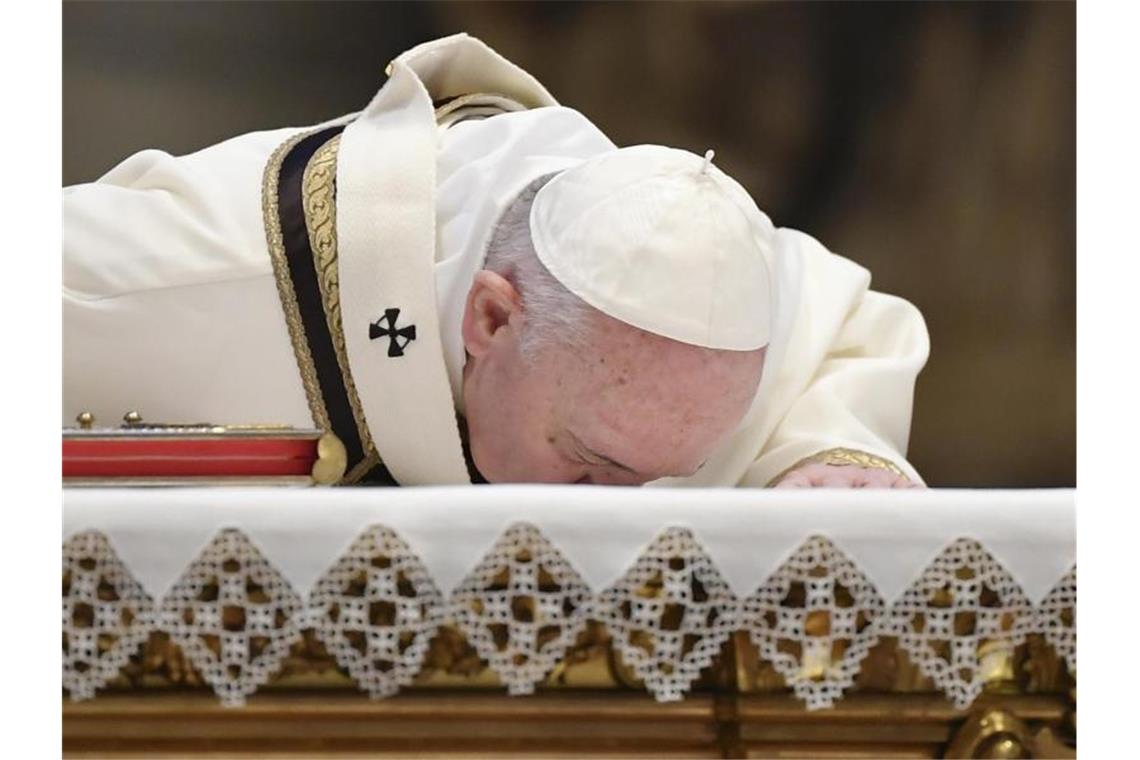 Papst Franziskus küsst zu Beginn der Ostermesse den Altar des fast leeren Petersdomes. Foto: Andreas Solaro/AFP/AP/dpa