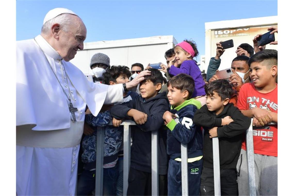 Papst Franziskus (l) legt einem Jungen im Flüchtlingslager auf der Insel Lesbos die Hand auf den Kopf. Foto: Vatican Media/ANSA via ZUMA Press/dpa