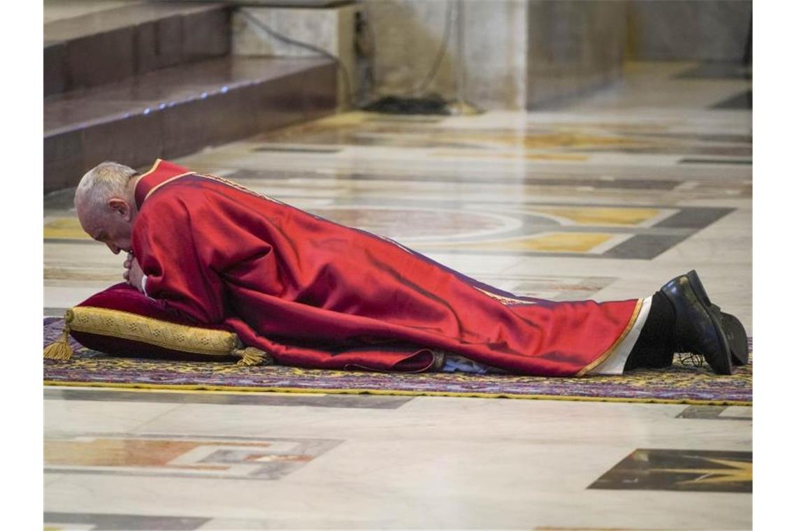 Papst Franziskus wirft sich im Rahmen der Feier vor der traditionellen Kreuzweg-Prozession im Altarraum des Petersdoms nieder. Foto: Andrew Medichini/AP/dpa