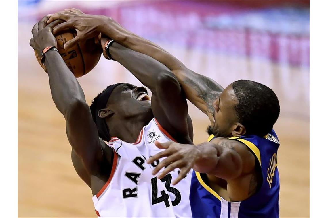 Pascal Siakam (l) von den Toronto Raptors im verteidigt den Ballbesitz gegen Andre Iguodala von den Golden State Warriors. Foto: Frank Gunn/The Canadian Press/AP