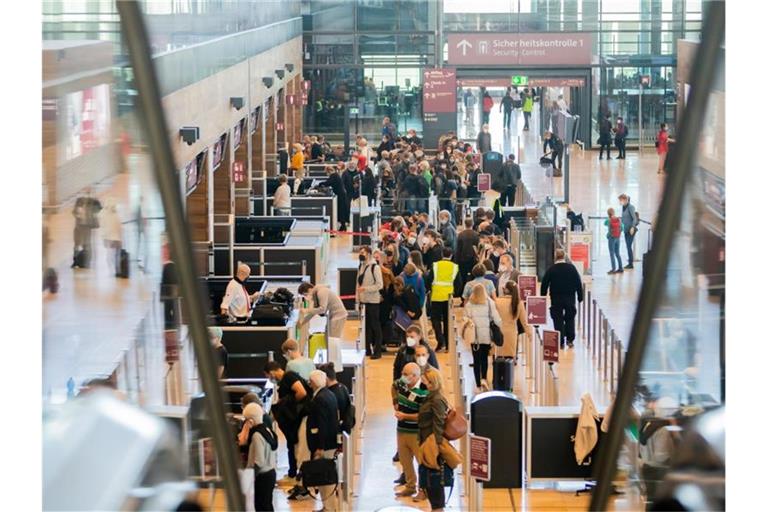 Passagiere am Hauptstadtflughafen Berlin Brandenburg „Willy Brandt“ (BER) vor der Sicherheitskontrolle. Verärgerte Fluggäste mussten etwa am Samstag zum Teil mehr als zwei Stunden auf das Einchecken warten. Foto: Christoph Soeder/dpa