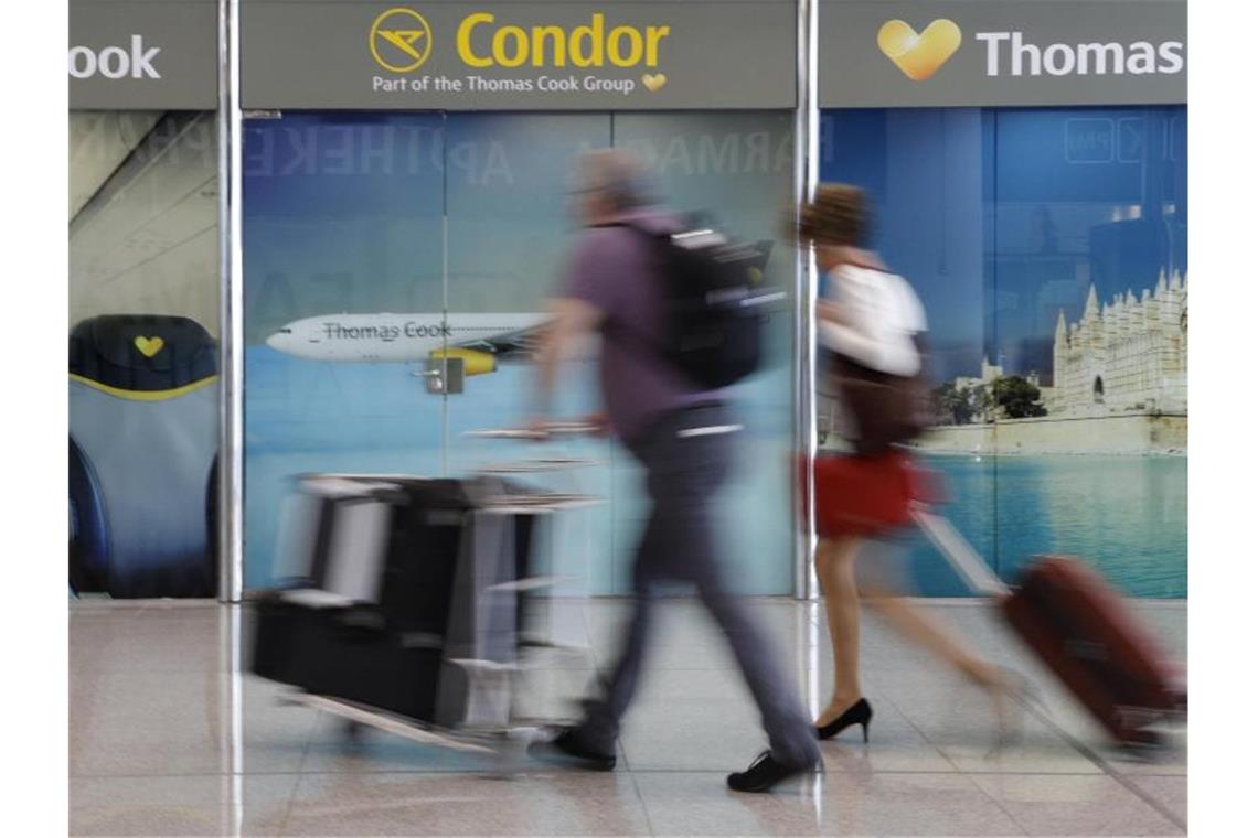Passagiere gehen an einem Büro von Condor und Thomas Cook am Flughafen Palma de Mallorca vorbei. Foto: Clara Margais