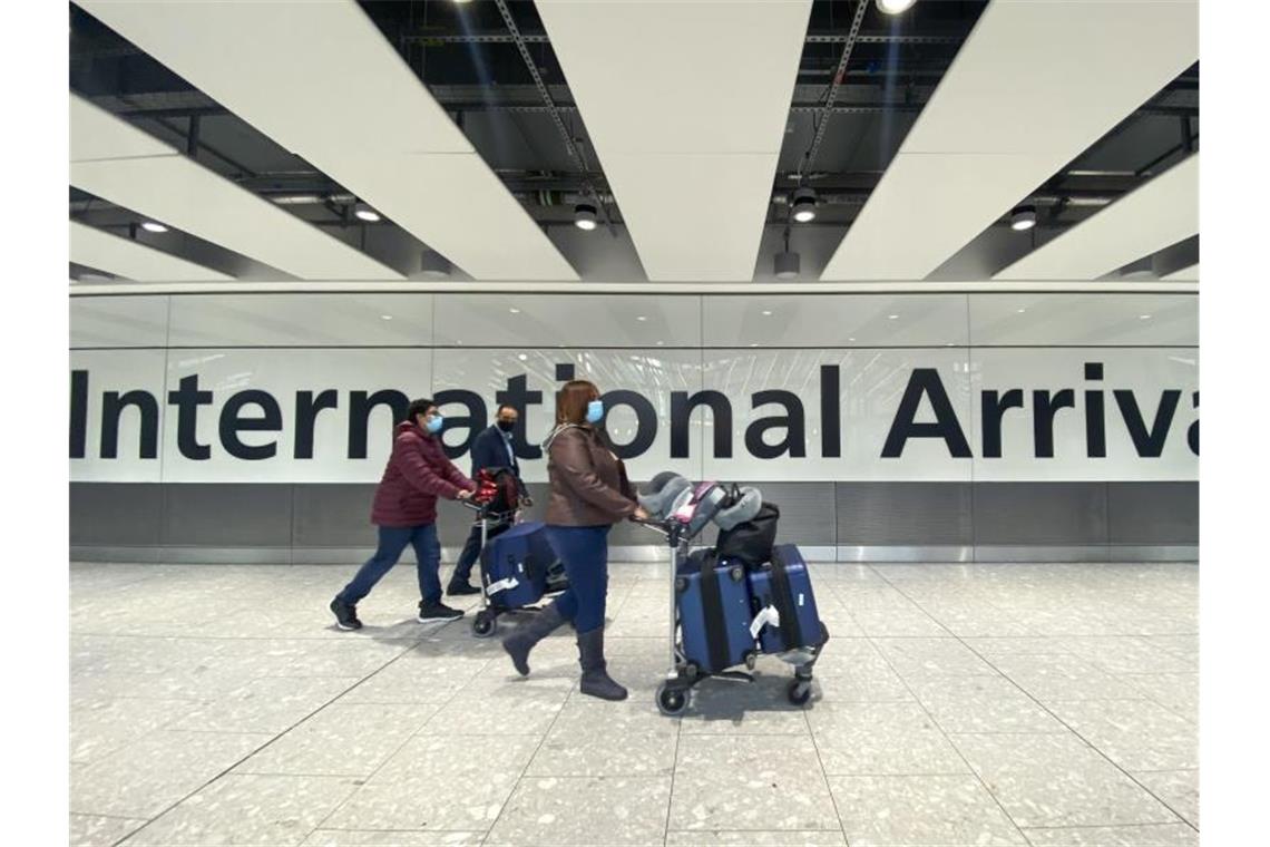 Passagiere gehen mit ihrem Gepäck durch das Ankunftsterminal eines Flughafens. Symbolbild. Foto: Alberto Pezzali/AP/dpa