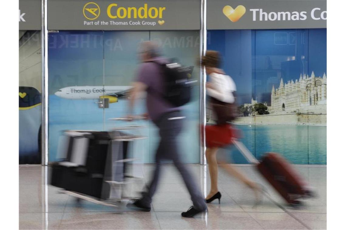 Passagiere neben einem Werbeschild von Thomas Cook am Flughafen von Palma de Mallorca. Foto: Clara Margais