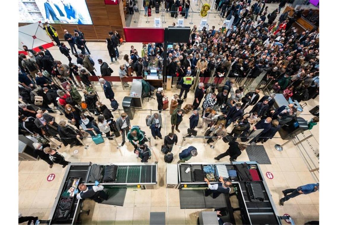 Passagiere stehen an einer Sicherheitskontrolle am Flughafen BER Schlange. Foto: Christophe Gateau/dpa