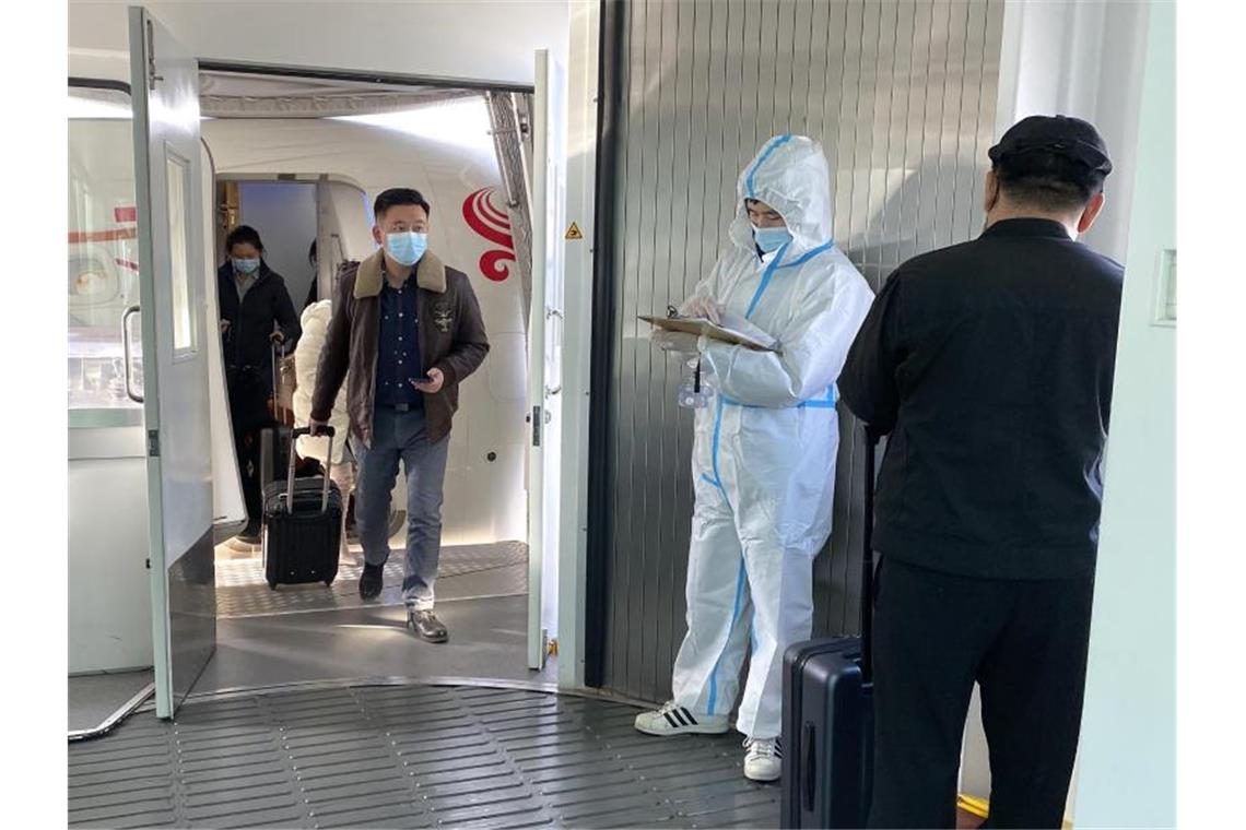 Passagiere tragen Schutzmasken und verlassen ein Flugzeug nach der Ankunft am Wuhan Tianhe International Airport. Foto: Ng Han Guan/AP/dpa