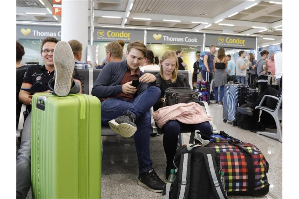 Passagiere warten in der Nähe des Büros von Condor und Thomas Cook im Flughafen von Palma de Mallorca. Foto: Clara Margais